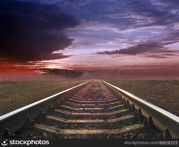 gloomy landscape with rails going away into the far sunset. gloomy landscape with rails going away into the far sunset. Evening landscape with rails