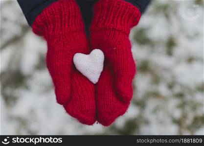 gloved hands holding white heart