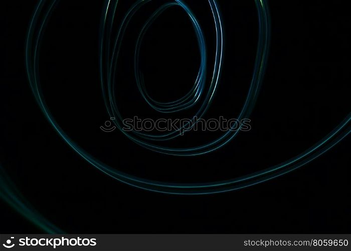 Glowing abstract curved lines.Blue colors.Black background.Done by long exposure technique
