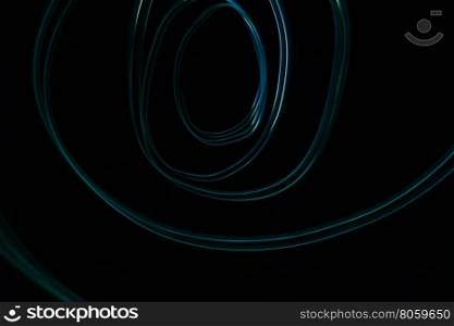 Glowing abstract curved lines.Blue colors.Black background.Done by long exposure technique