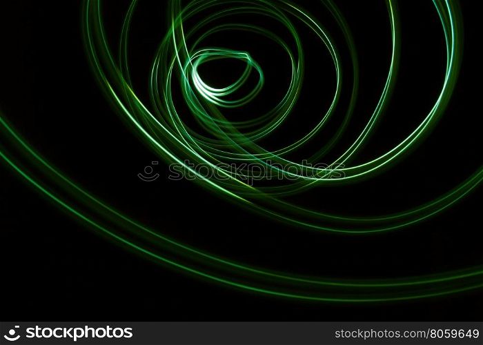 Glowing abstract curved lines.Green colors.Black background.Done by long exposure technique
