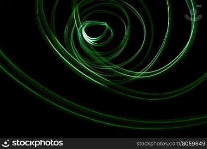 Glowing abstract curved lines.Green colors.Black background.Done by long exposure technique