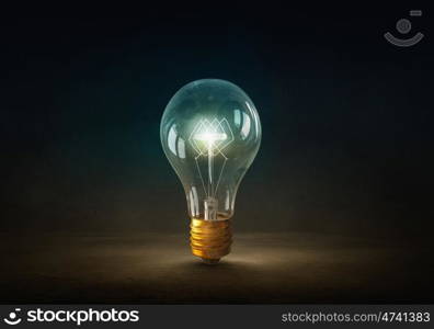 Glowing bulb. Glowing glass light bulb on dark background