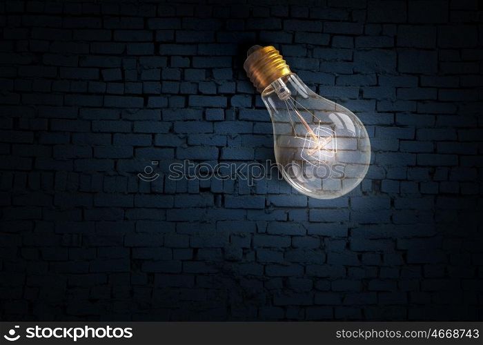 Glowing bulb on brick surface. One turned on light bulb on brick wall background