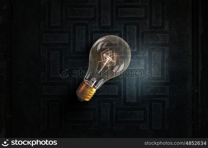 Glowing bulb on brick surface. One turned on light bulb on brick wall background