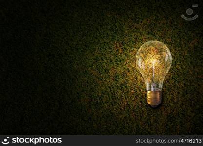 Glowing bulb on stone surface. One turned on light bulb on stone wall background