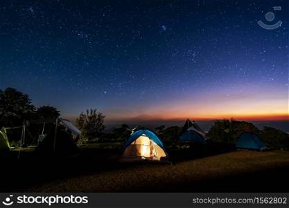 Glowing camping tent on the mountain under a beautiful starry sky at night, Travel lifestyle