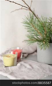 glowing candles on linen textile next to cement vase with pine tree branch. aesthetic composition home decor and cozy ambience. vertical.. glowing candles on linen textile next to cement vase with pine tree branch. aesthetic composition home decor and cozy ambience. vertical