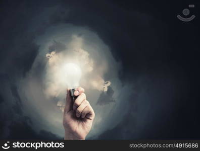 Glowing electric bulb . Hand holding glass glowing lightbulb in darkness