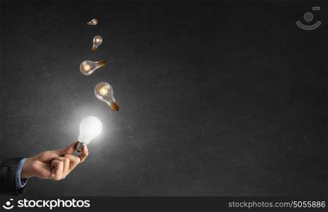 Glowing electric bulb . Hand holding glass glowing lightbulb in darkness