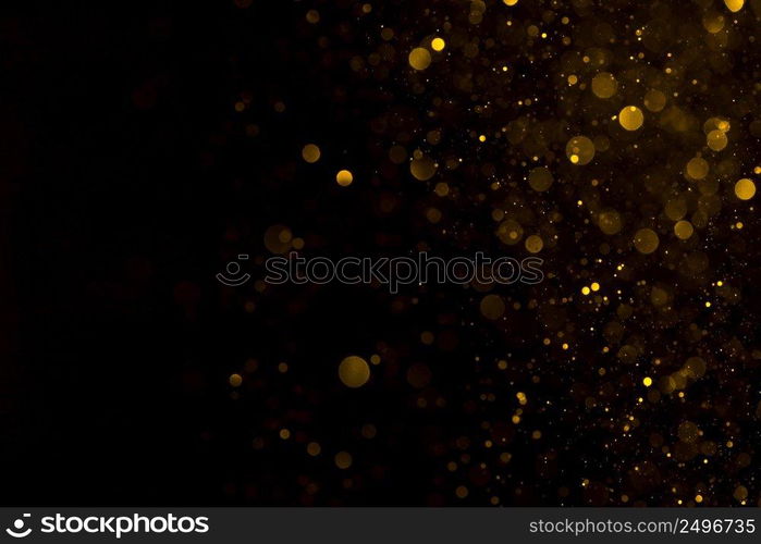 Glowing golden dust spark particles falling on black background