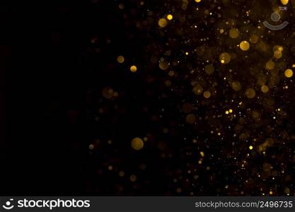 Glowing golden dust spark particles falling on black background