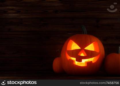Glowing Halloween pumpkin heads jack o lantern on wooden background. Glowing Halloween pumpkins