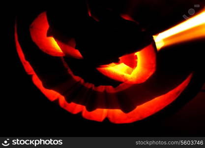 Glowing Halloween pumpkin with rays of light on black background