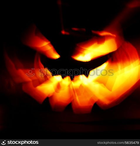 Glowing Halloween pumpkin with rays of light on black background