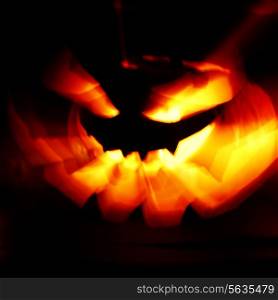 Glowing Halloween pumpkin with rays of light on black background