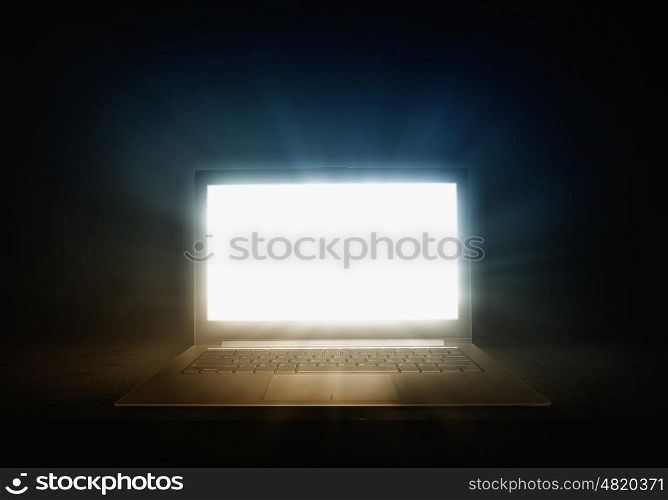 Glowing laptop. Open laptop with light coming from screen on dark background