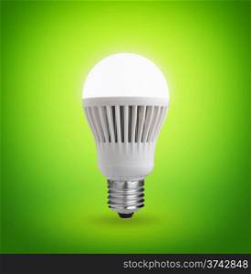Glowing LED bulb on green background