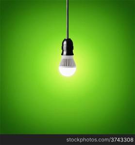 Glowing led bulb on green background