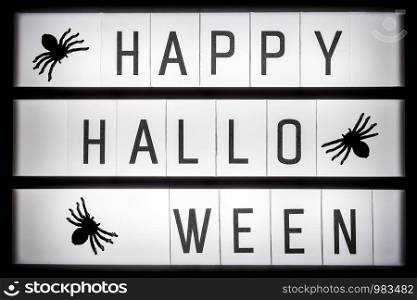 Glowing lightbox with text Happy halloween and spiders, closeup. Halloween concept, Top view, Flat lay, Template for greeting card.. Glowing lightbox with text Happy halloween and spiders, closeup. Halloween concept, Top view, Flat lay, Template for greeting card