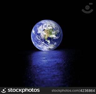Glowing Planet earth on wet asphalt. Earth image provided by NASA.