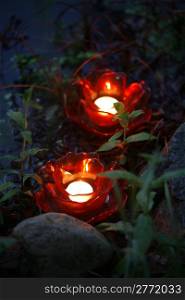 Glowing red candles by water