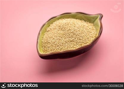 gluten free amaranth grain in a small ceramic leaf shaped bowl against pink background