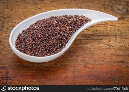 gluten free black quinoa grain grown in Bolivia , a teardrop shaped bowl against rustic grunge wood with a copy space