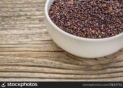 gluten free, black quinoa grain in a small, ceramic bowl against grained wood