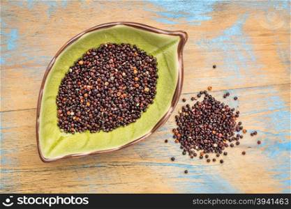 gluten free black quinoa grain on a leaf shaped bowl against grunge wood
