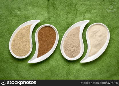 gluten free brown and ivory teff grain and flour on teardrop shaped bowls against green textured paper - important food grain in Ethiopia and Eritrea