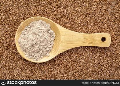 gluten free brown teff grain and flour - wooden spoon against seed background