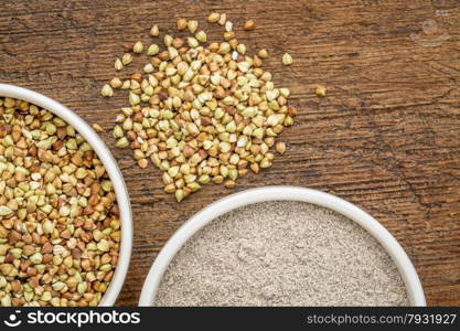 gluten free buckwheat grain and flour - top view of two ceramic bowls against rustic wood