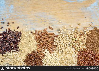 gluten free grains (buckwheat, amaranth, brown rice, millet, sorghum, teff, red and black quinoa, kaniwa) on a grunge painted wood - top view background with a copy space