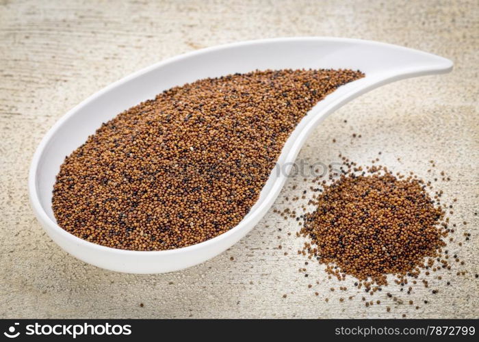 gluten free kaniwa grain on a teardrop shaped bowl against white painted rustic wood