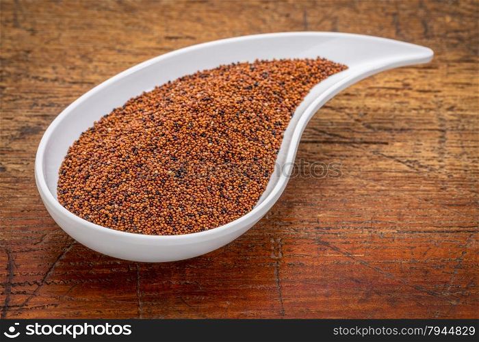 gluten free kaniwa grain on a white teardrop shaped bowl against rustic wood