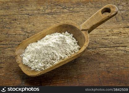 gluten free quinoa flour on a wooden scoop against weathered wood