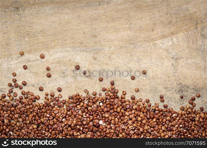 gluten free red quinoa grain against textured handmade bark paper