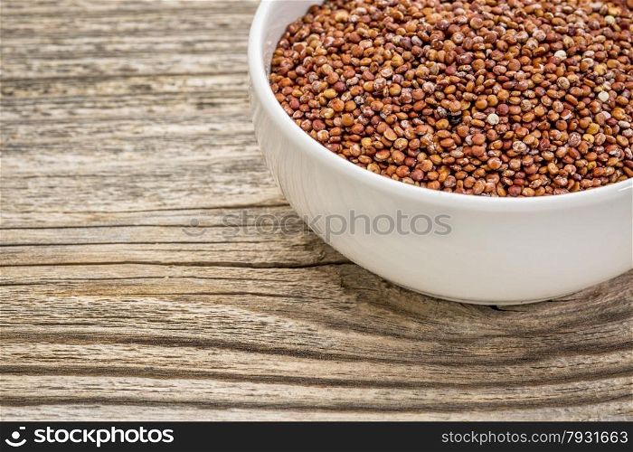 gluten free, red quinoa grain in a small, ceramic bowl against grained wood