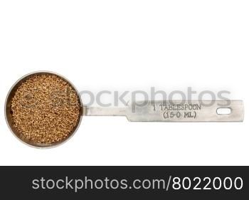gluten free teff grain in a metal measuring tablespoon isolated on white
