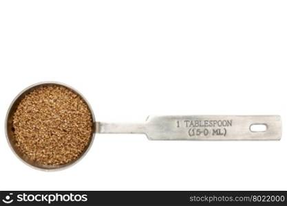 gluten free teff grain in a metal measuring tablespoon isolated on white