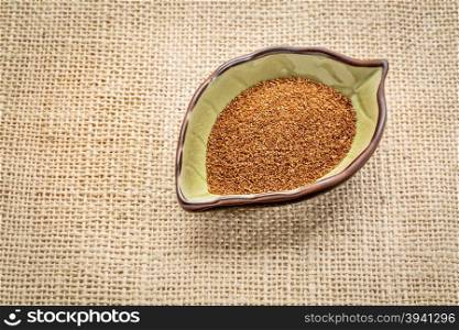 gluten free teff grain on a leaf shaped bowl against burlap canvas