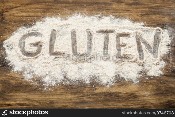 gluten word written in wheat flour on wooden board