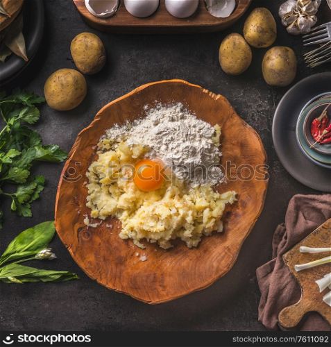 Gnocchi dough ingredients. Potatoes with egg and flour in wooden bowl on dark kitchen table with organic ingredients for tasty home cooking. Food preparation. Frame. Top view. Vintage cuisine