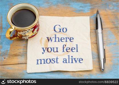 Go where you feel most alive - inspirational handwriting on a napkin with a cup of coffee