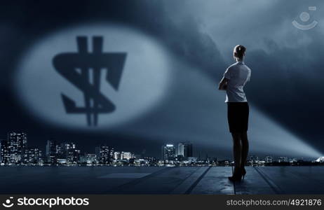 Goal is to become rich. Businesswoman standing with back in darkness and dollar sign in spothlight