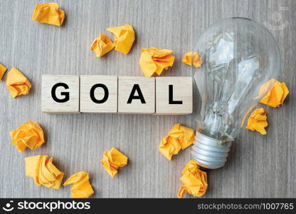 GOAL text wood cube and crumbled paper with lightbulb on wooden table background. Creative, Innovation, Imagination, inspiration, Solution, Strategy and IDEAS concept