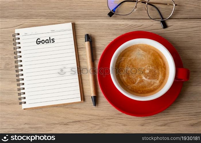 GOAL with notebook and coffee cup on wood table. Motivation, Resolution, To do list, Strategy and Plan concept