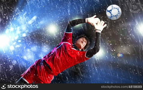 Goalkeeper catches the ball . At the stadium, in the spotlight.