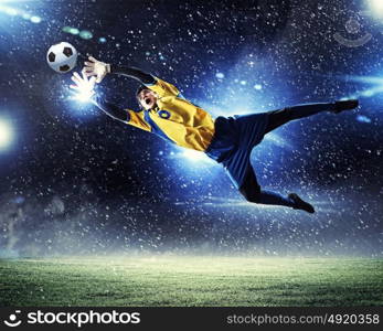 Goalkeeper catches the ball. Goalkeeper catches the ball . At the stadium, in the spotlight.